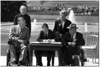 Bush signs the Americans with Disabilities Act on July 26, 1990 and says, "Let the shameful walls of