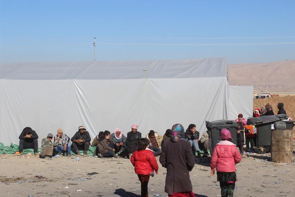 Men sitting outside one of the rubhall tents. Most families stay a matter of hours in the reception centre and are then transported onwards.