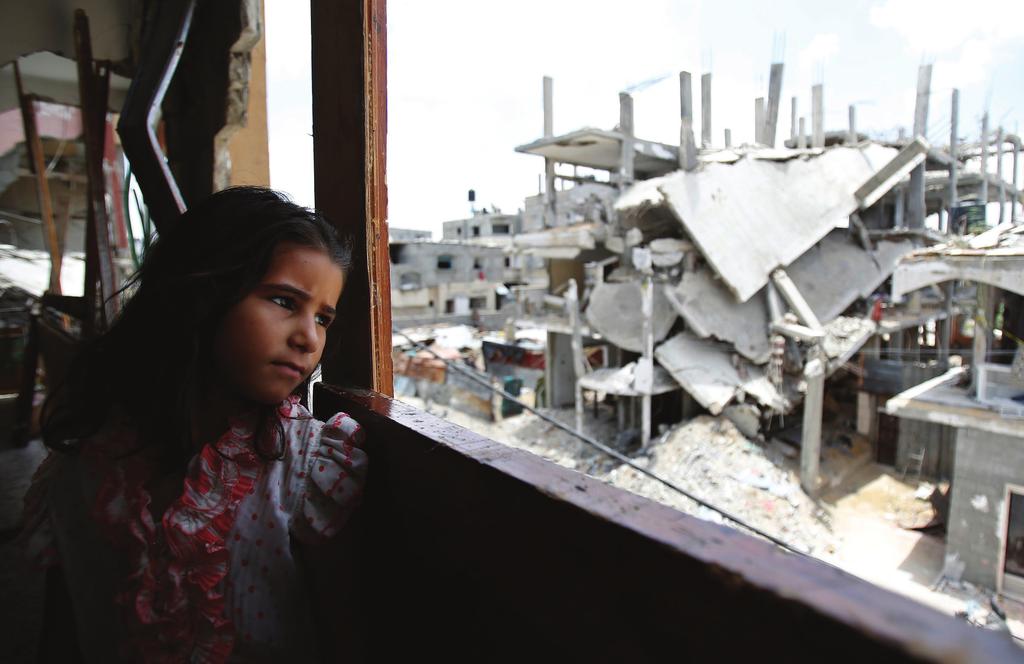 A girl looks out from her family s partially destroyed home at the destruction in Shejaiya neighbourhood of Gaza City. The house was it during an air strike a year ago.