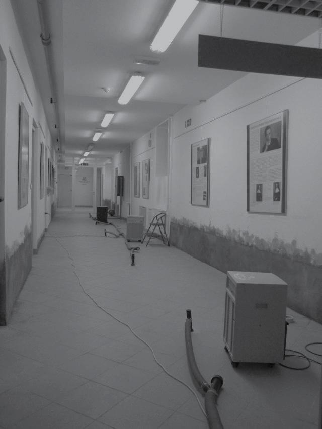 Slika 5: Vakuumsko izsuševanje tal v hodniku arhiva škofjeloške enote Zgodovinskega arhiva Ljubljana, kjer so vidne tudi z novim ometom sanirane stene.