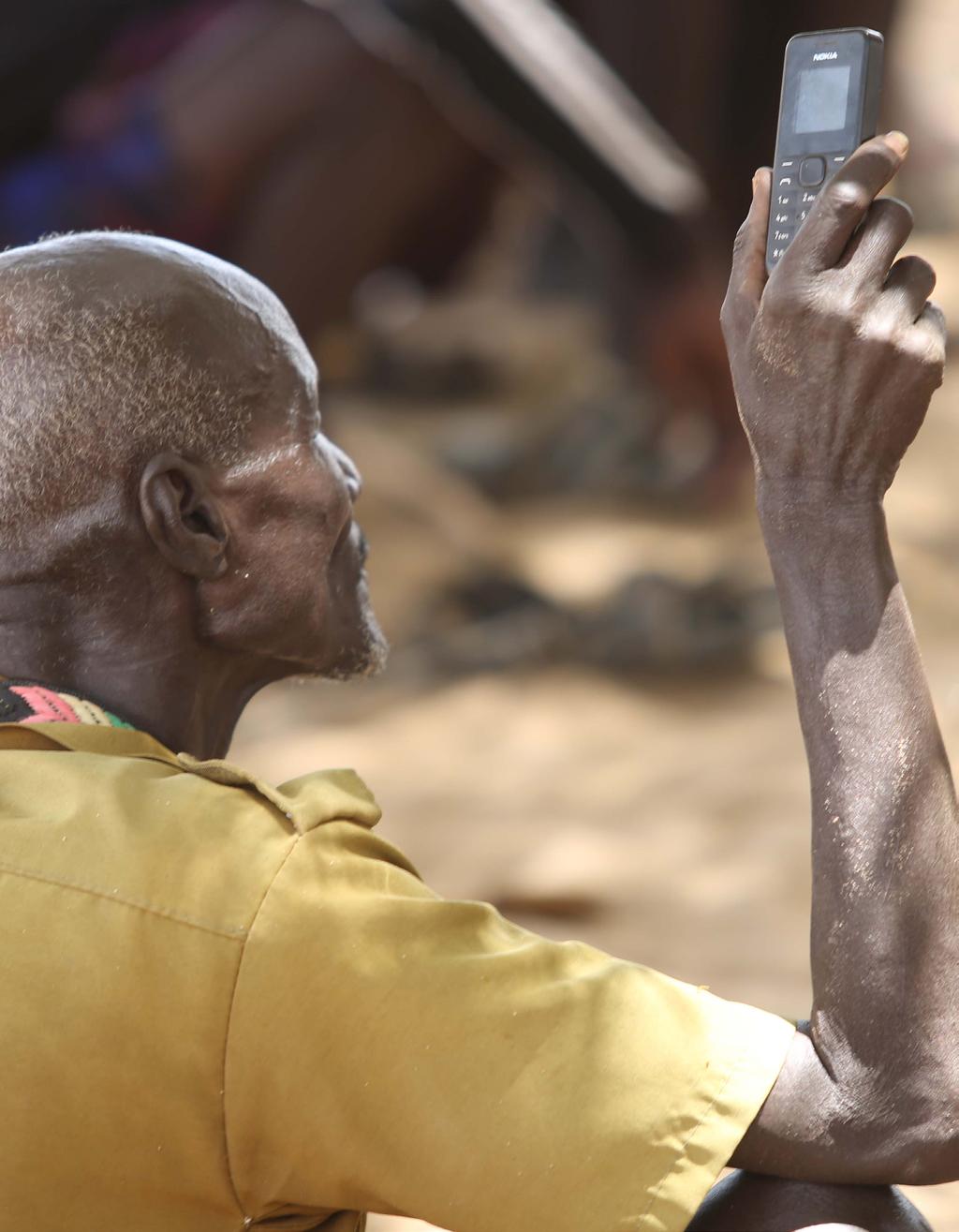 Our services reach over 2 million people every year A Turkana elder holds out his mobile phone during a public baraza discussing