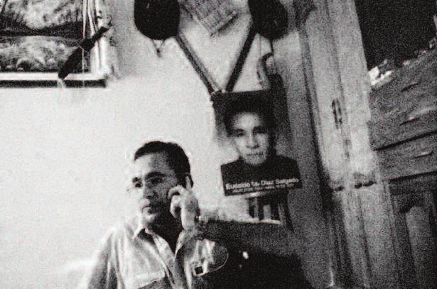Juan David Diaz Chamorro speaks on the phone in his room. A poster of his father, Eudaldo Tito Diaz, former mayor of Roble, Sucre, is seen in the background.