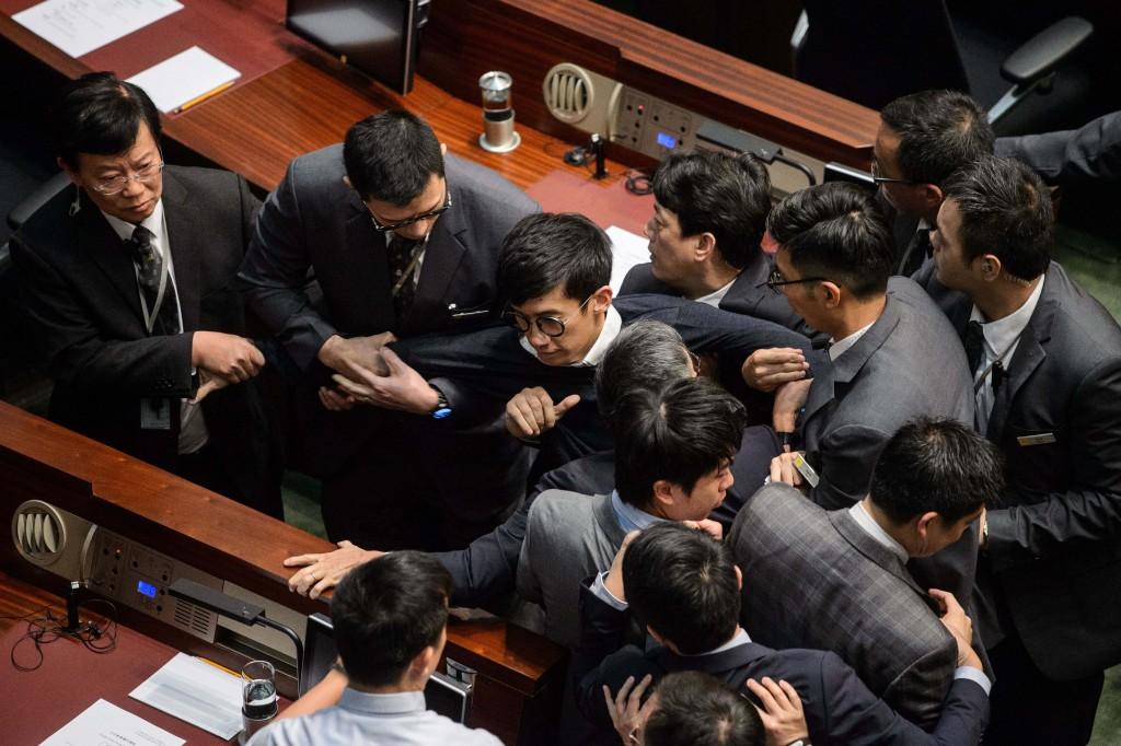 Newly elected lawmaker Sixtus Baggio Leung, center, is restrained by security guards after attempting to read a Legislative Council oath in Hong Kong, on Nov. 2, 2016.