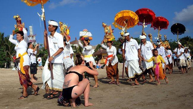 4. Tourism & Human Rights Balinese dressed in traditional clothing walk on a beach