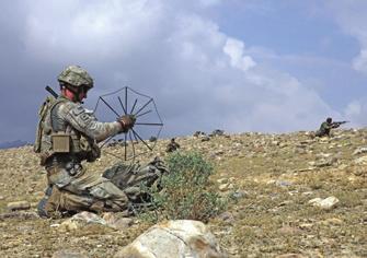 A U.S. soldier (left) sets up tactical satellite communications while an Afghan soldier shoots at enemy fighters in the Shekhabad Valley, Wardak Province, Afghanistan, in August.