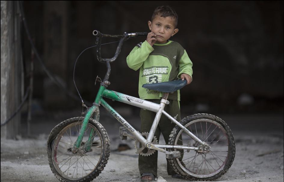 Syria refugee card 31 Sam Tarling/Oxfam Qusay plays with his bike.