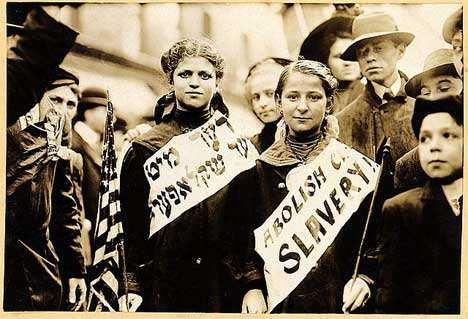 Two girls wearing banners with slogan "ABOLISH CH[ILD] SLAVERY!