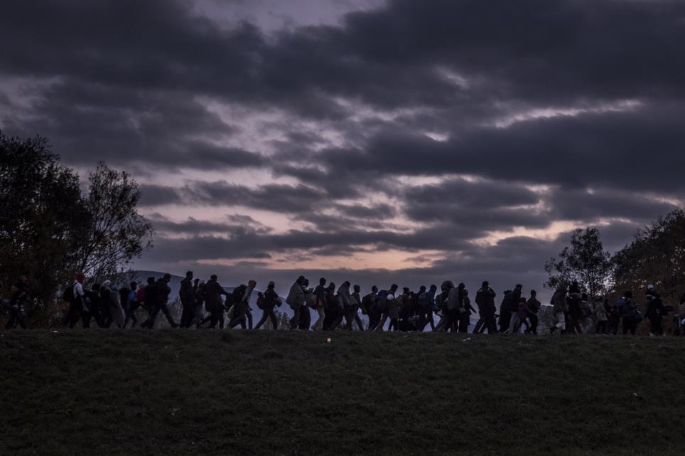 Oct. 23, 2015. Migrants walking along a dyke, escorted by Slovenian riot police, to a registration camp outside Dobova.