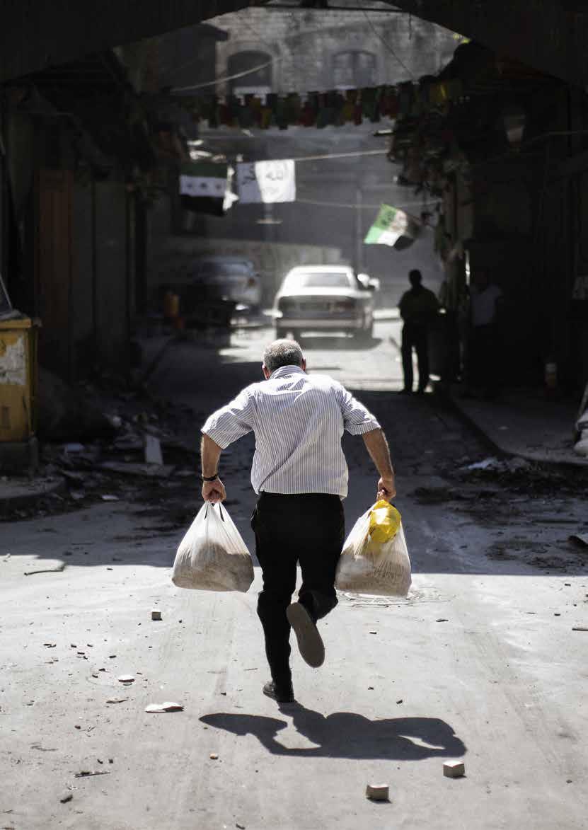 A Syrian man carrying grocery bags tries to dodge sniper fire as he runs through an alley near a checkpoint manned by the Free Syria Army in the northern city of Aleppo on September 14