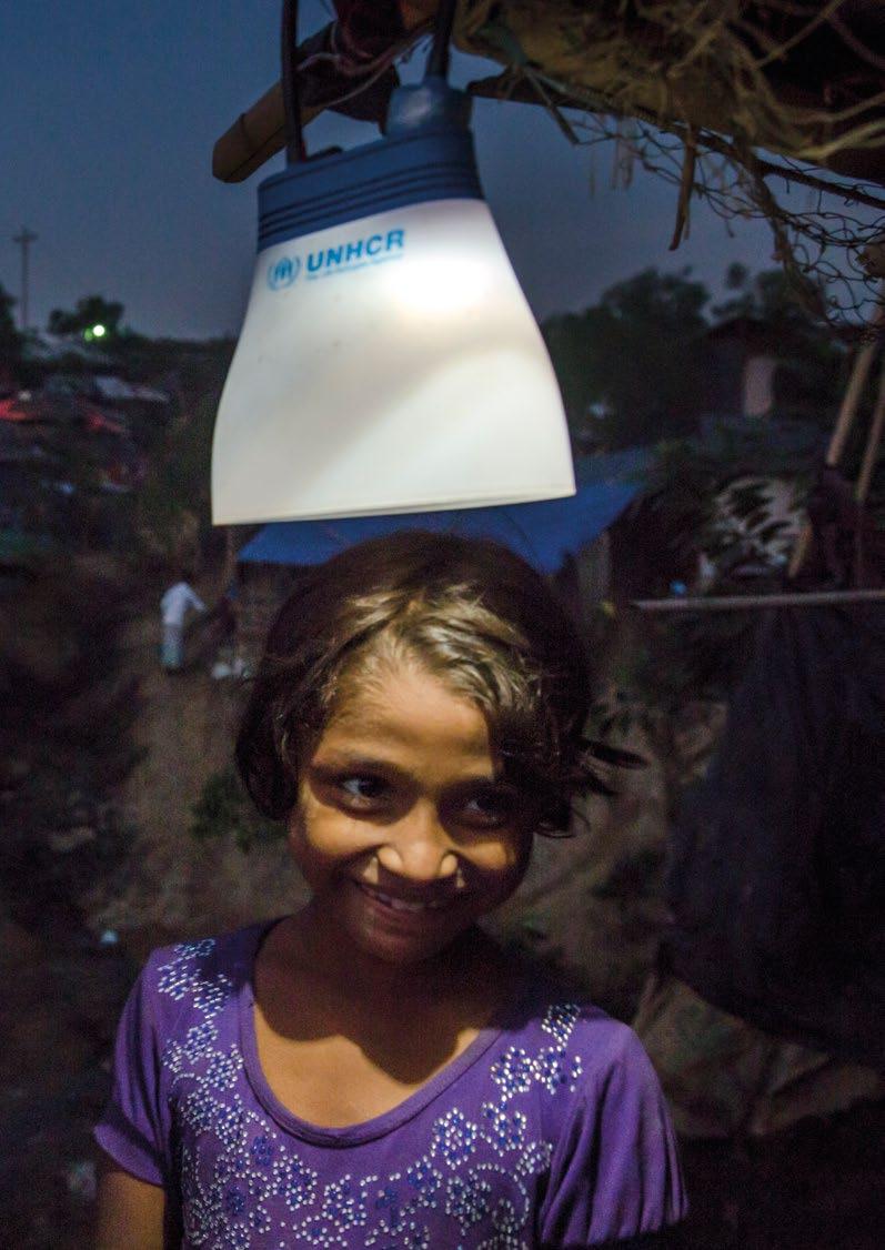 Bangladesh. An eight-year-old Rohingya refugee girl stands beneath a UNHCR solar lantern outside her shelter at Kutupalong camp in Bangladesh.