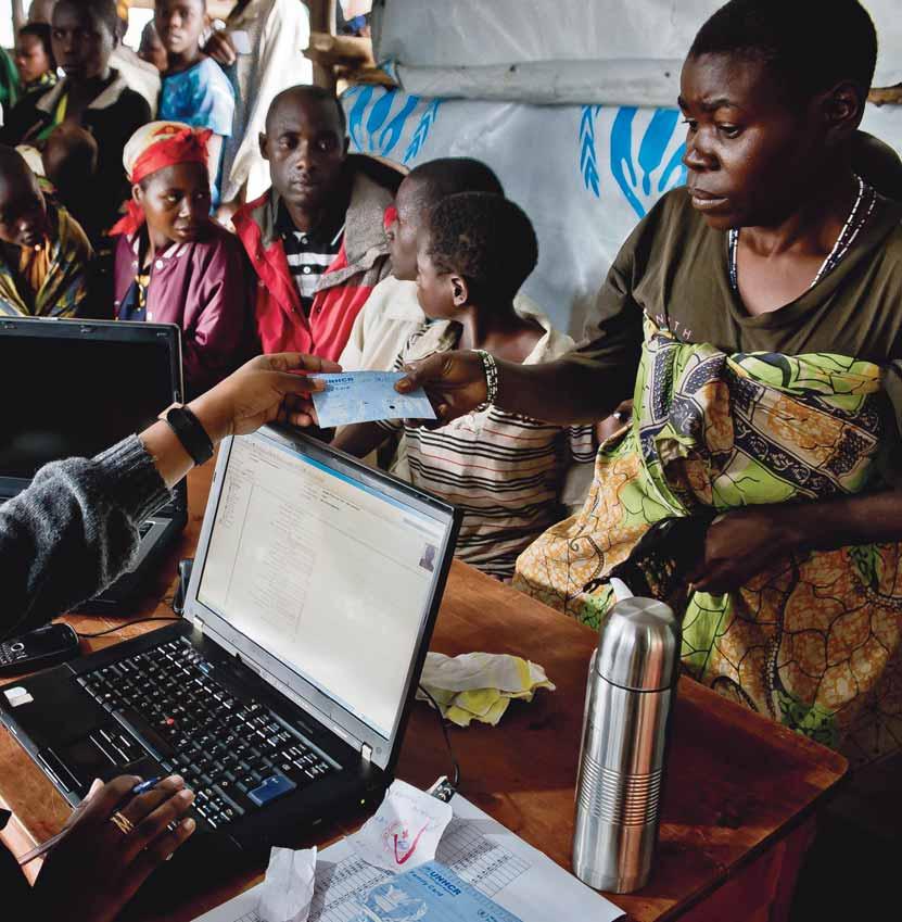 A UNHCR staff member gives an ID card to a Congolese woman who has just registered as a refugee with her