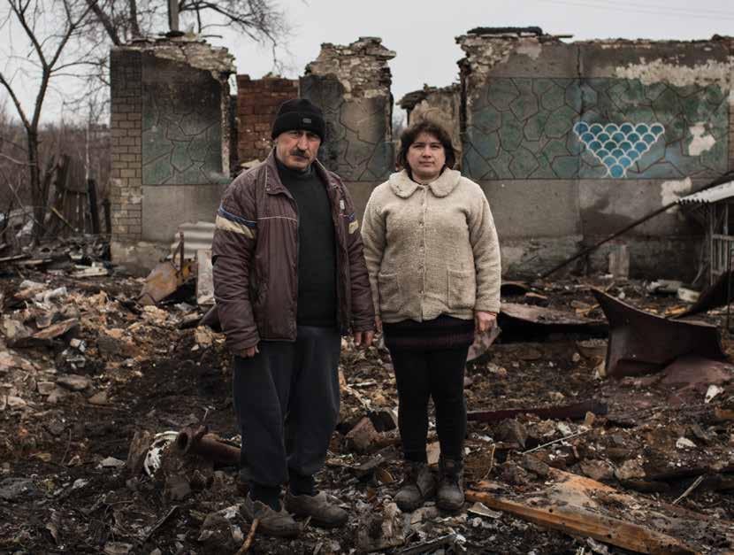 Yurvi and Tatiana stand in the ruins of their family home in Nikishino, eastern Ukraine.