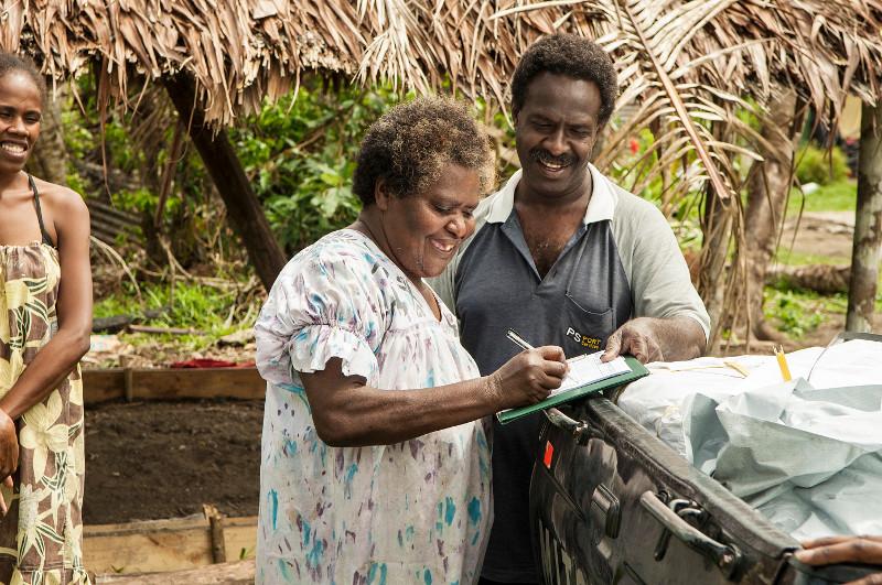 Photo by Corrie Sissons/CRS. VANUATU A woman receives a tarp following Cyclone Pam in March 2015.