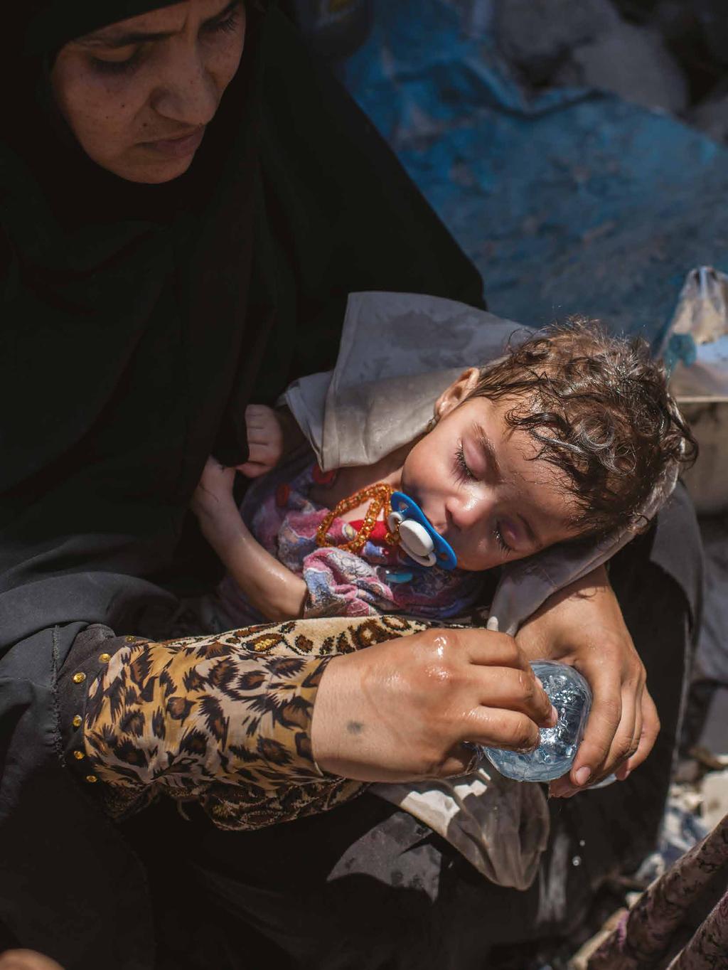 INTRODUCTION Iraq. People fleeing fighting in the old city of Mosul. A mother sprinkles water on her young child while fighting continues unabated in Mosul in June 2017.
