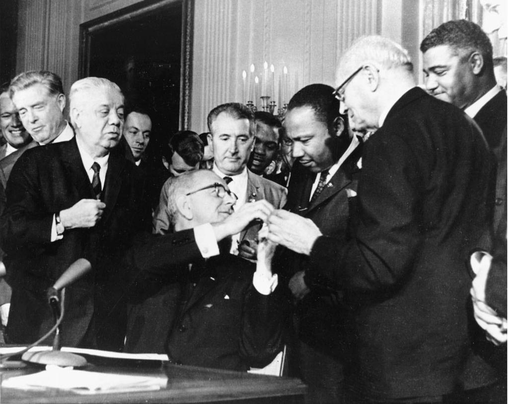 The Civil Rights Act of 1964 President Johnson reaches to shake hands with Dr. Martin Luther King Jr.