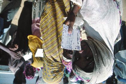An Eritrean refugee in eastern Sudan is queuing to receive her monthly food ration, with her UNHCR card in hand. UNHCR / P.