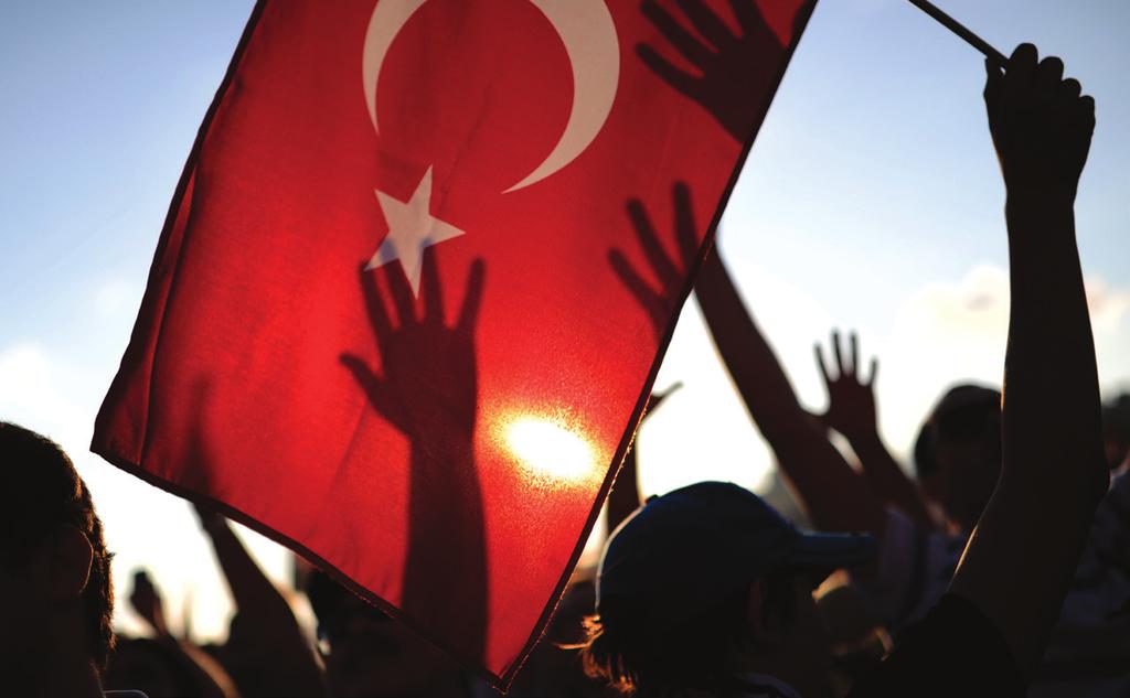 5 A protester holds up a Turkish flag as others raise their hands during a demonstration in Taksim Square in Istanbul.