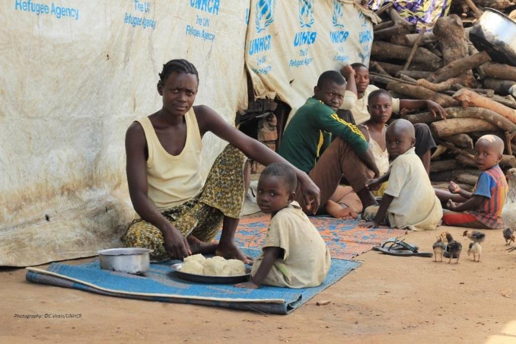A Burundian refugee mother and her child sit down for a meal of fufu and beans at the gathering point of Sange, DRC. UNHCR / C.