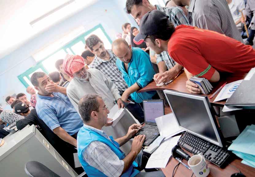 UNHCR staff answer questions for refugees at a help desk in the city of Zarqa, Jordan.