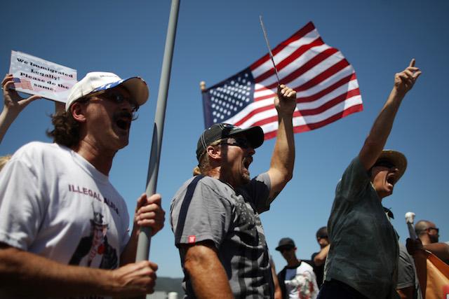 Protesters who oppose arrivals of buses carrying largely women and children undocumented migrants for processing at the Murrieta Border Patrol Station yell at counter-demonstrators on July 4, 2014 in