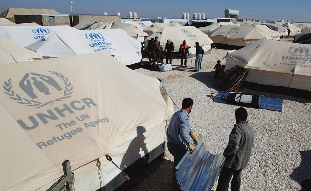 Refugees employed by the Norwegian Refugee Council, a key UNHCR implementing partner, carry metal sheeting that will be used to create