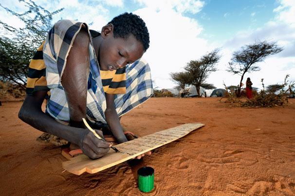 ACT/Paul Jeffrey Abden Barl Keinan, 15, writes out verses from the Koran during an Islamic class in the Dadaab