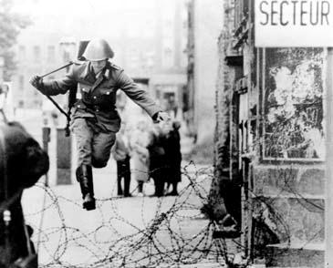 A photograph of East German soldier, Hans Conrad Schuhmann, leaping across the barbed wire fence to West Berlin and freedom,