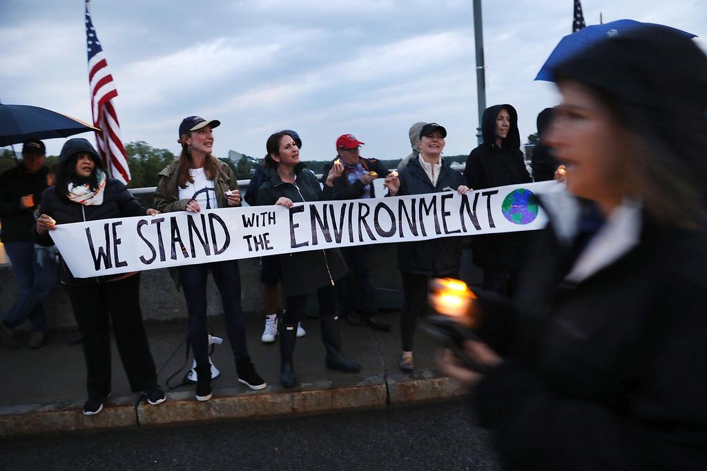 Dozens of Connecticut residents converge along a bridge at a vigil and rally for the environment and against President Donald Trump's recent decision to withdraw the United States from the Paris