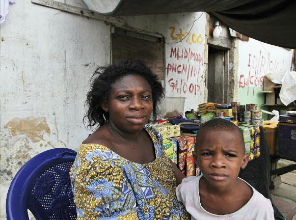 A woman and her son outside their home in Abonnema Wharf, Port Harcourt, Nigeria its walls marked for demolition.