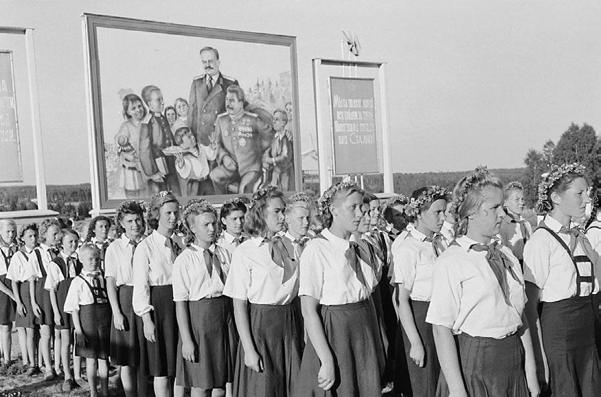 Members of a Russian youth group called Young Communists line up for a parade. Notice the picture of Stalin in the background. activity and protect the citizens.