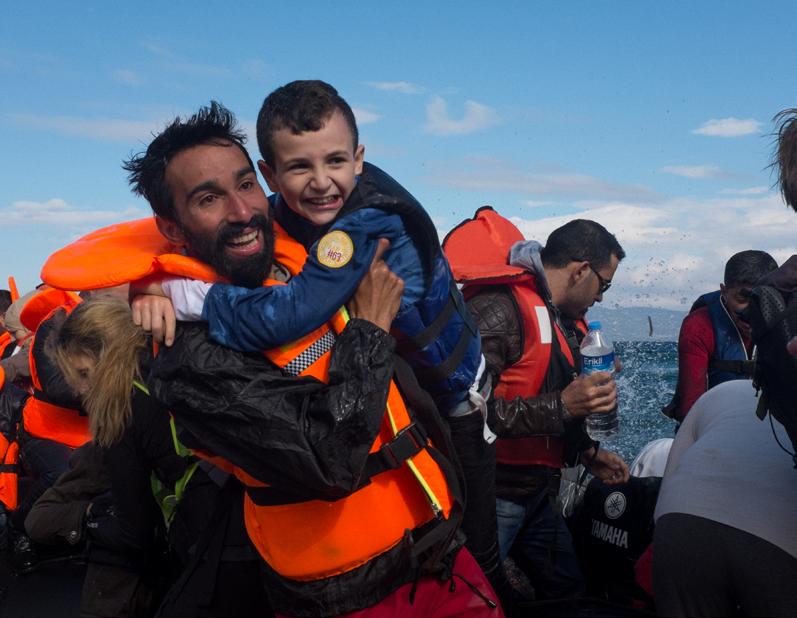 Unicef/Gilbertson DANGEROUS JOURNEYS: GREECE PHOTO SHEET 9 A volunteer welcomes refugees arriving from Syria, and helps a boy climb out of a dinghy.
