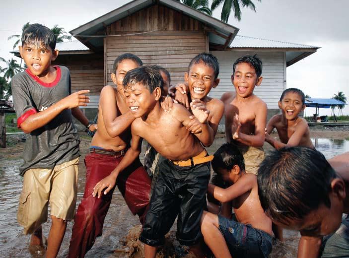 Young boys play in front of a community center built by UNHCR in Padang Datar village, Krueng Sabee district, Indonesia. Photo courtesy of UNHCR/J. Perugia.